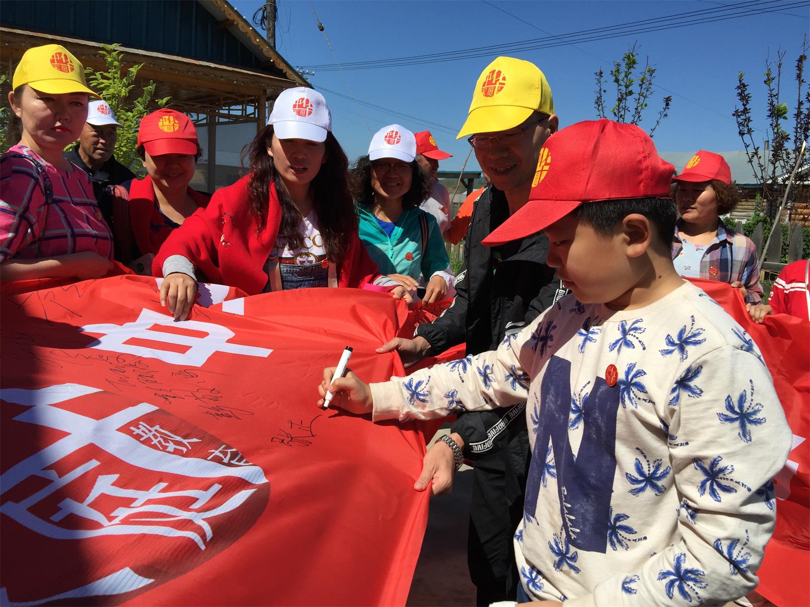 儿子张正作为志愿者在条幅上签名,一起参加内蒙古恩和乡俄罗斯民族村的家庭教育精准帮扶志愿活动。.JPG